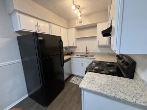 a kitchen with black appliances and white cabinets at The  Cedars